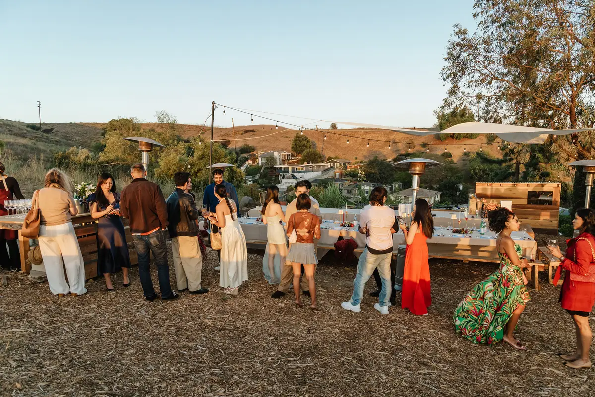 Guests mingling outdoors at golden hour before dinner
