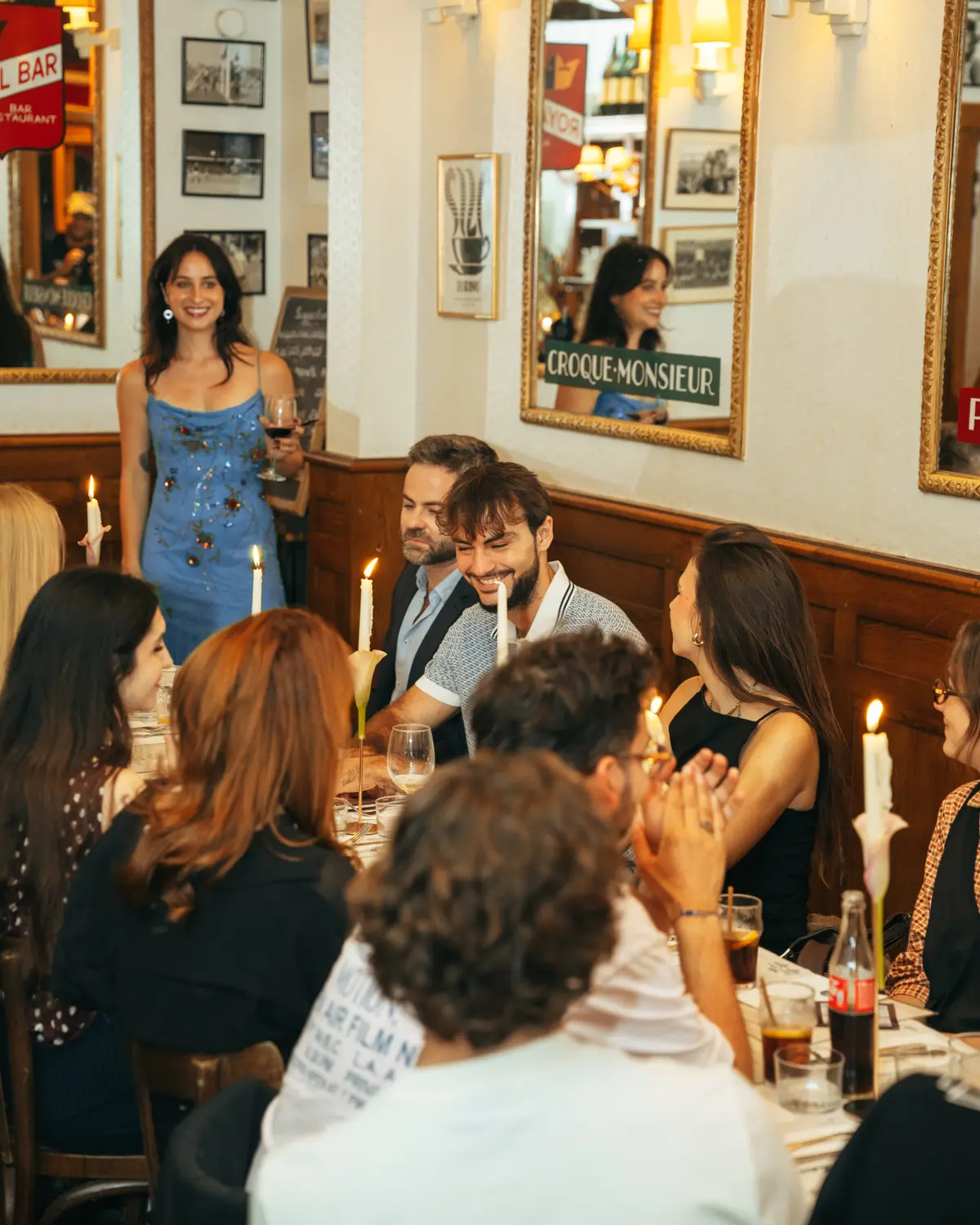 Guests at the table as a guest in a blue dress raises a glass