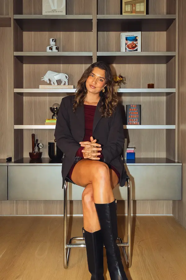 A guest seated on a stool in front of a bookcase