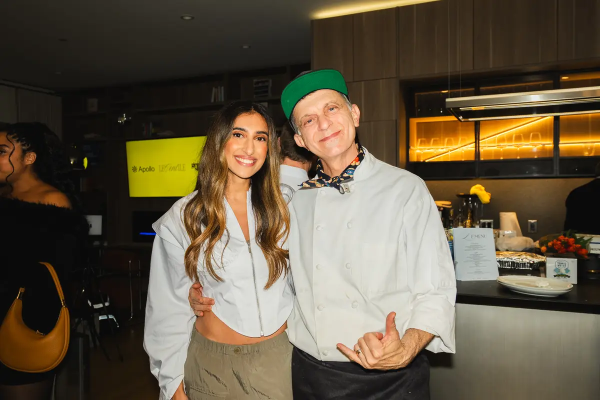 Two guests smiling, one in a green cap